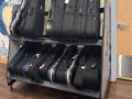 a grey and black shelf rack holding violin cases, next to a wall painted with  an ocean wave, and a door on the other side