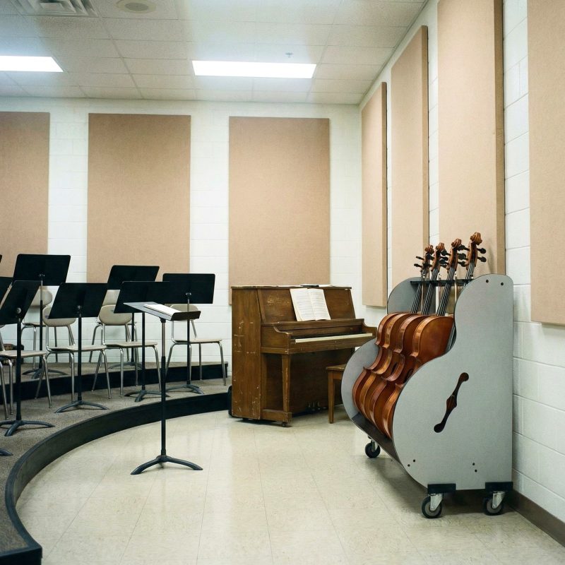 multi cello stand placed in a music classroom with risers and a piano