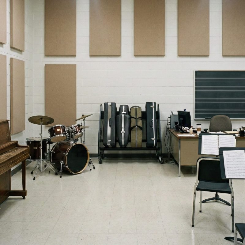 School classroom with saxophone cases, piano, drum set and student chairs