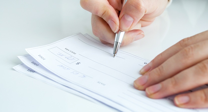 Closeup image of young businesswoman filling personal banking cheque